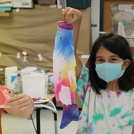 Child holding up their painted fish art project