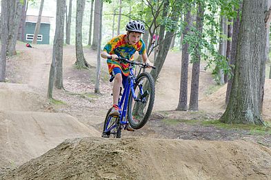 young cyclist on a dirt jump at bike park