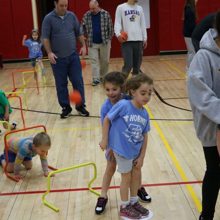 Young children playing in a gym at basketball camp
