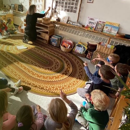 children sitting in circle listening to teacher