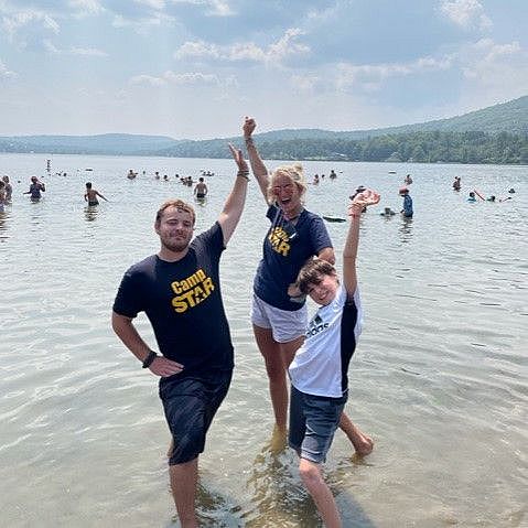 child and camp counselors playing in a lake